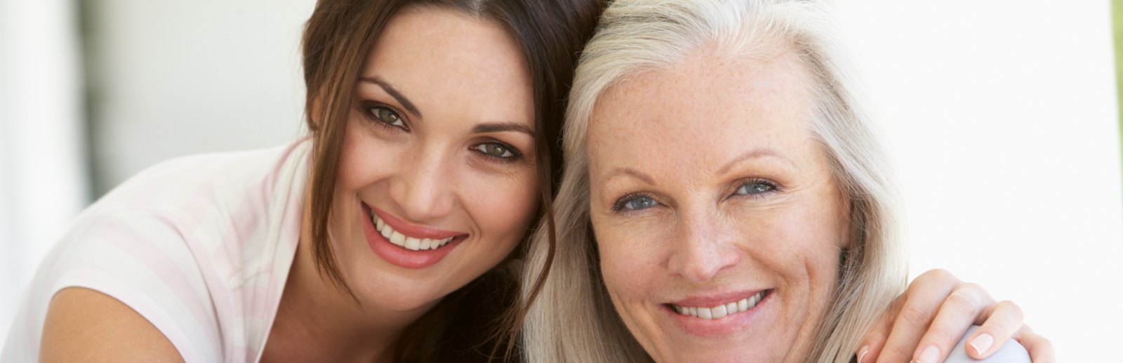A smiling young woman with her arm around an older woman