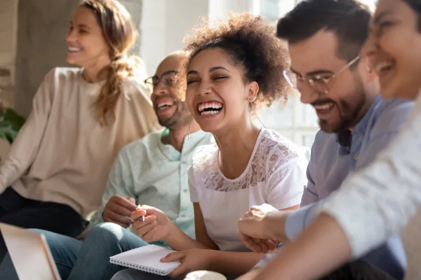 Training for therapists: a group of people laughing together, one holding a notebook